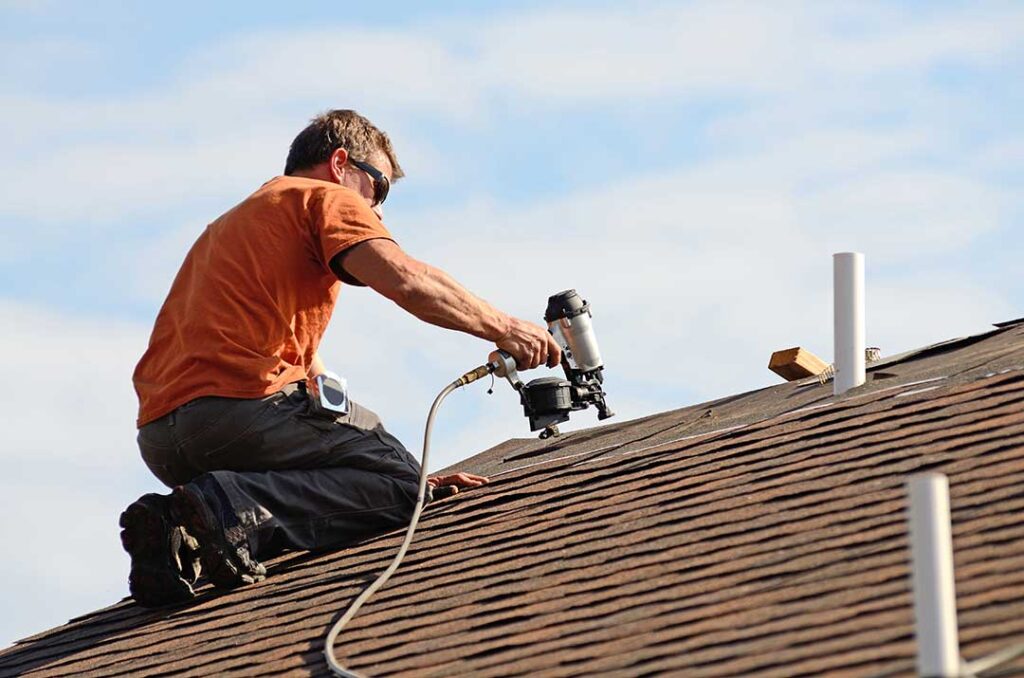 Peeling ceiling paint and a dark water stain in a home’s upper room caused by a roof leak.