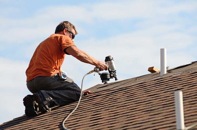 Peeling ceiling paint and a dark water stain in a home’s upper room caused by a roof leak.