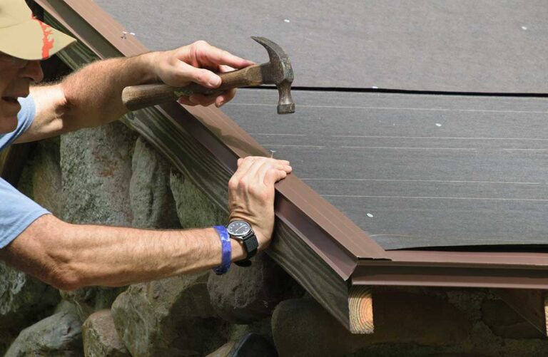 Homeowner inspecting roof gutters and shingles from the ground beside a snow-ready house.